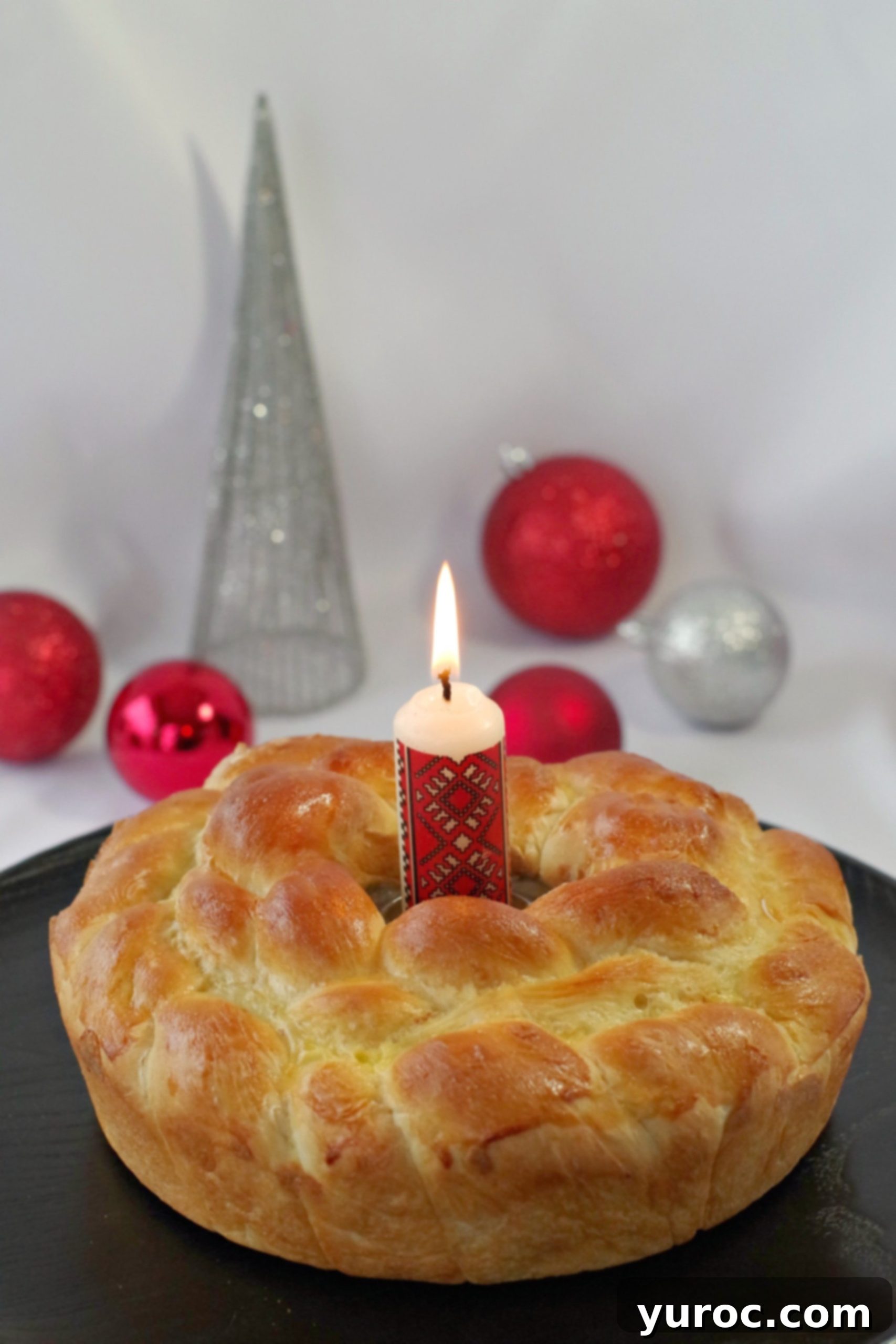 Kolach Ukrainian Christmas Bread on black platter with Ukrainian candle in the middle and Christmas decorations in the backgro