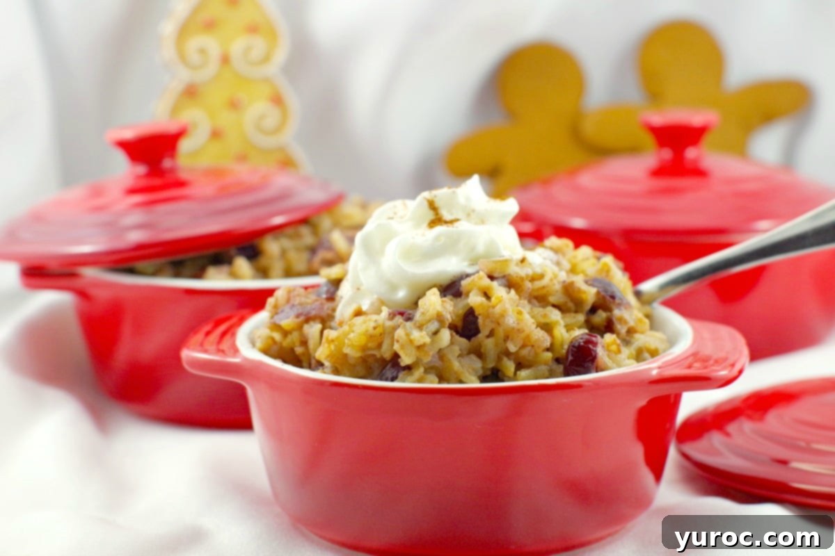 Cranberry Gingerbread pudding in a red bowl with more red bowls in the background and a gingerbread tree and gingerbread men