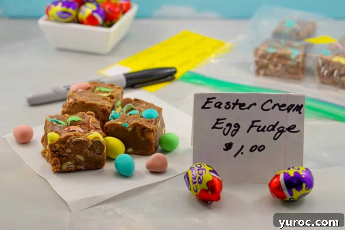 Three squares of Easter Egg Fudge arranged on a piece of parchment paper with a homemade bake sale price sign in front, highlighting its appeal for selling.