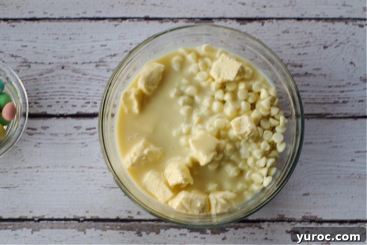 Milk chocolate chips, white chocolate chips, sweetened condensed milk, and butter measured and placed together in a large glass microwave-safe bowl, ready for melting.