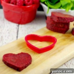 healthy jello hearts on cutting board with raspberries and spinach in the background