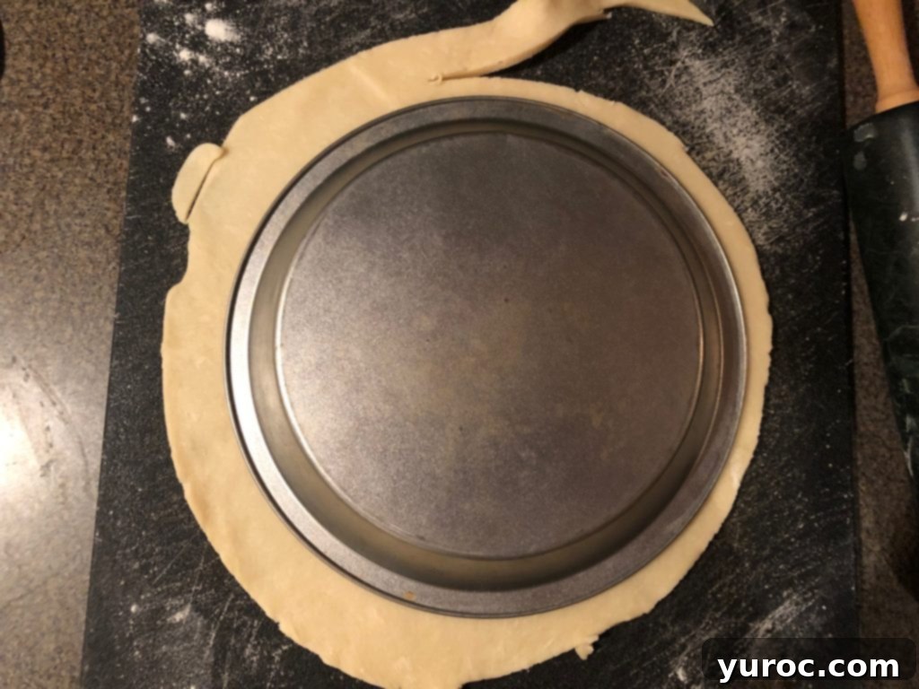 Pie crust with pie plate on top, being trimmed to size