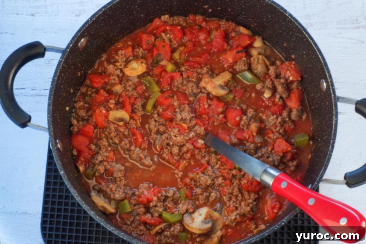 Completed spaghetti and meat sauce simmering in a large pot with a serving spoon