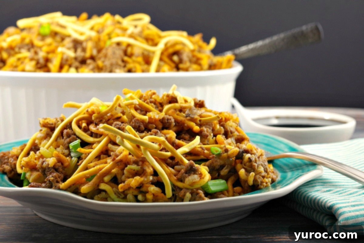 Hearty Chow Mein Hotdish 3 A single serving of Chow Mein Hotdish on a plate, with the larger casserole dish blurred in the background, showcasing the crispy noodle topping.
