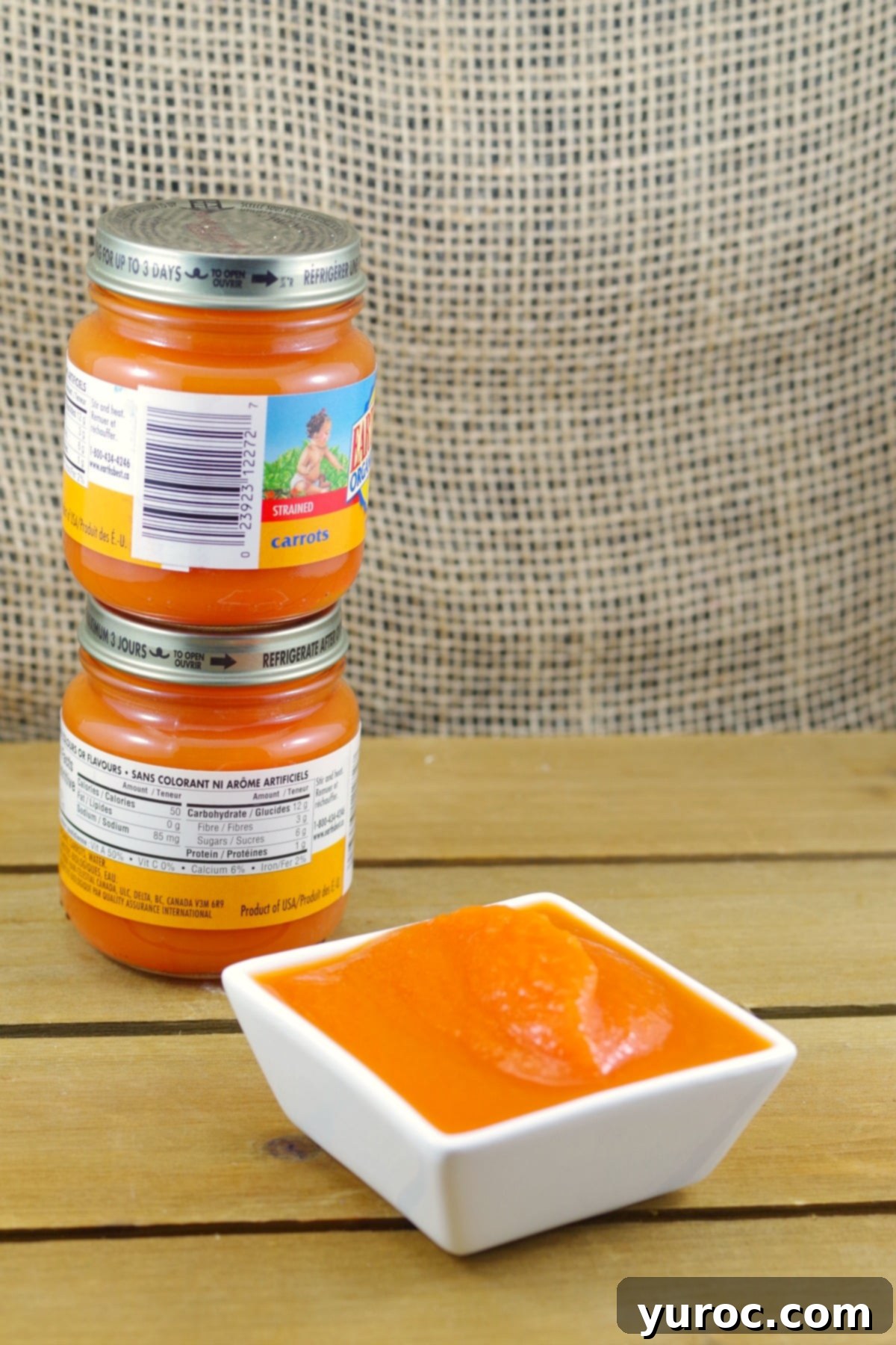 2 jars of baby food piled up behind a dish of carrot baby food