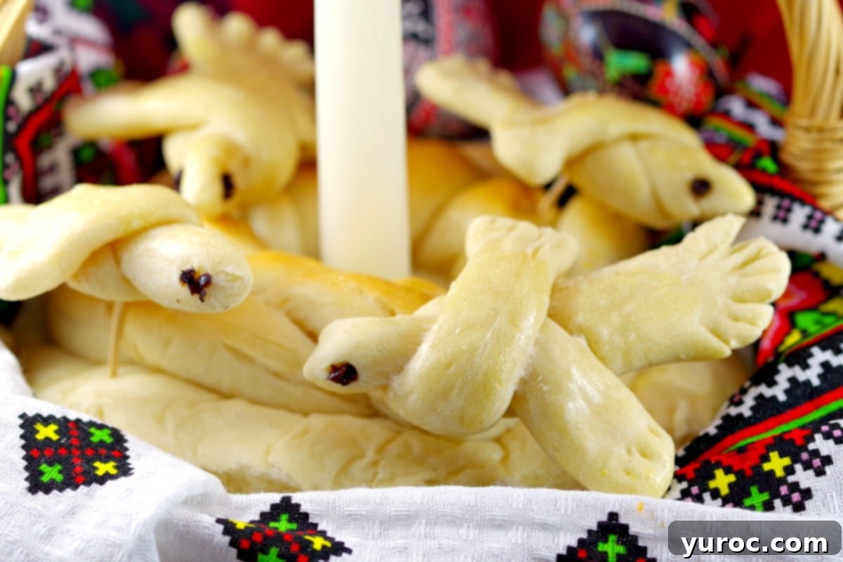 Ukrainian Easter Doves made of bread decorating a loaf of paska in basket (with candle in the middle)