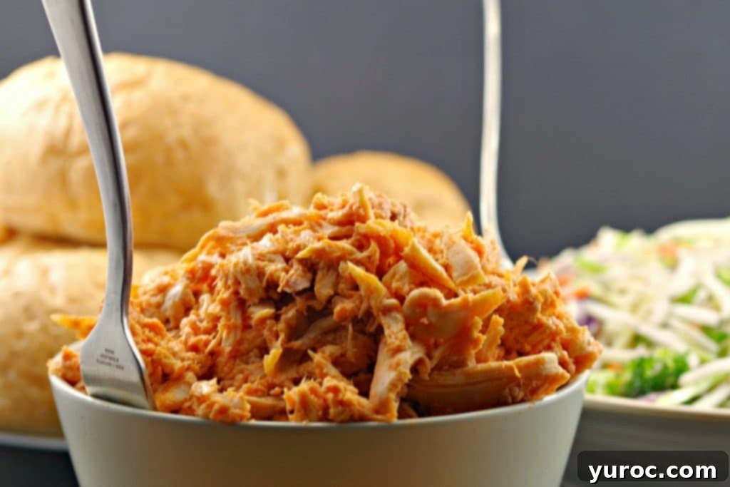 Bowl of buffalo pulled chicken with buns in the background