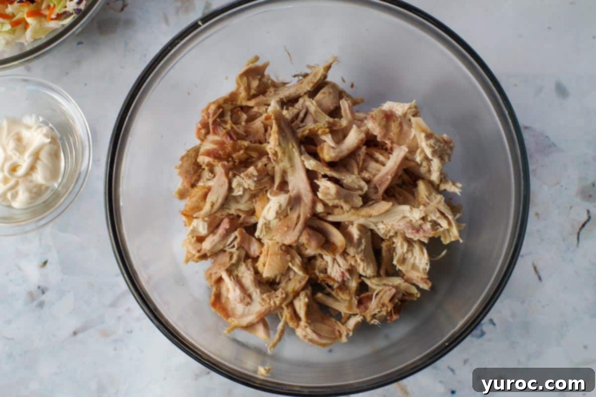 Chicken (removed from bone) in a large glass bowl.