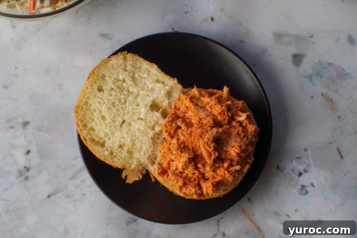 Buffalo chicken on a bun on a black plate.