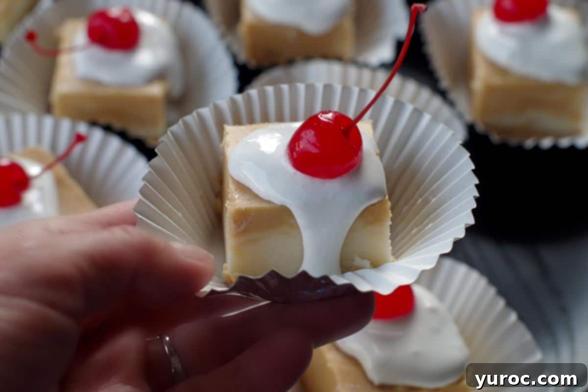 Dreamy Strawberry Milkshake Cookies 8 a piece of root beer float fudge being held up in front of a tray of more root beer float fudge