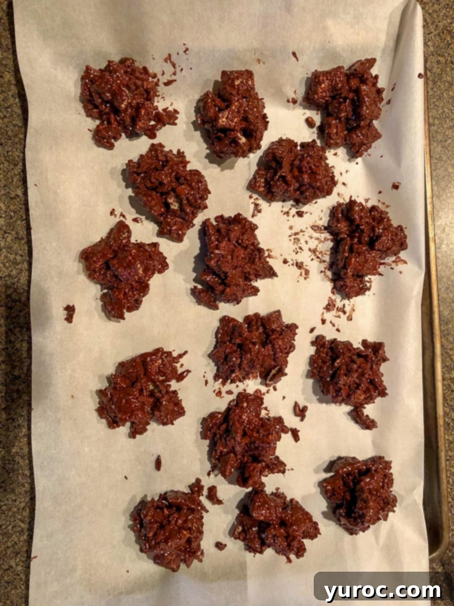 Finished chocolate clusters resting on a parchment-covered baking sheet, ready for chilling.