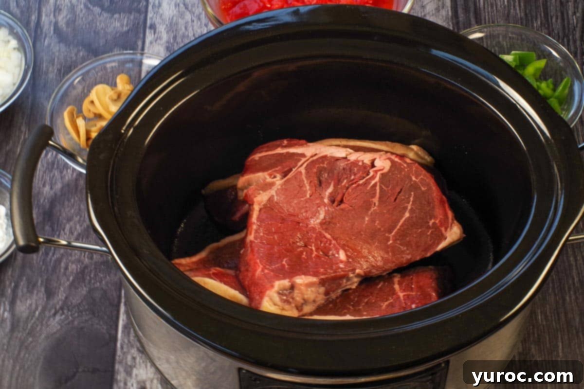 Slow Cooker Smothered Swiss Steak 5 Steak in the bottom of a slow cooker
