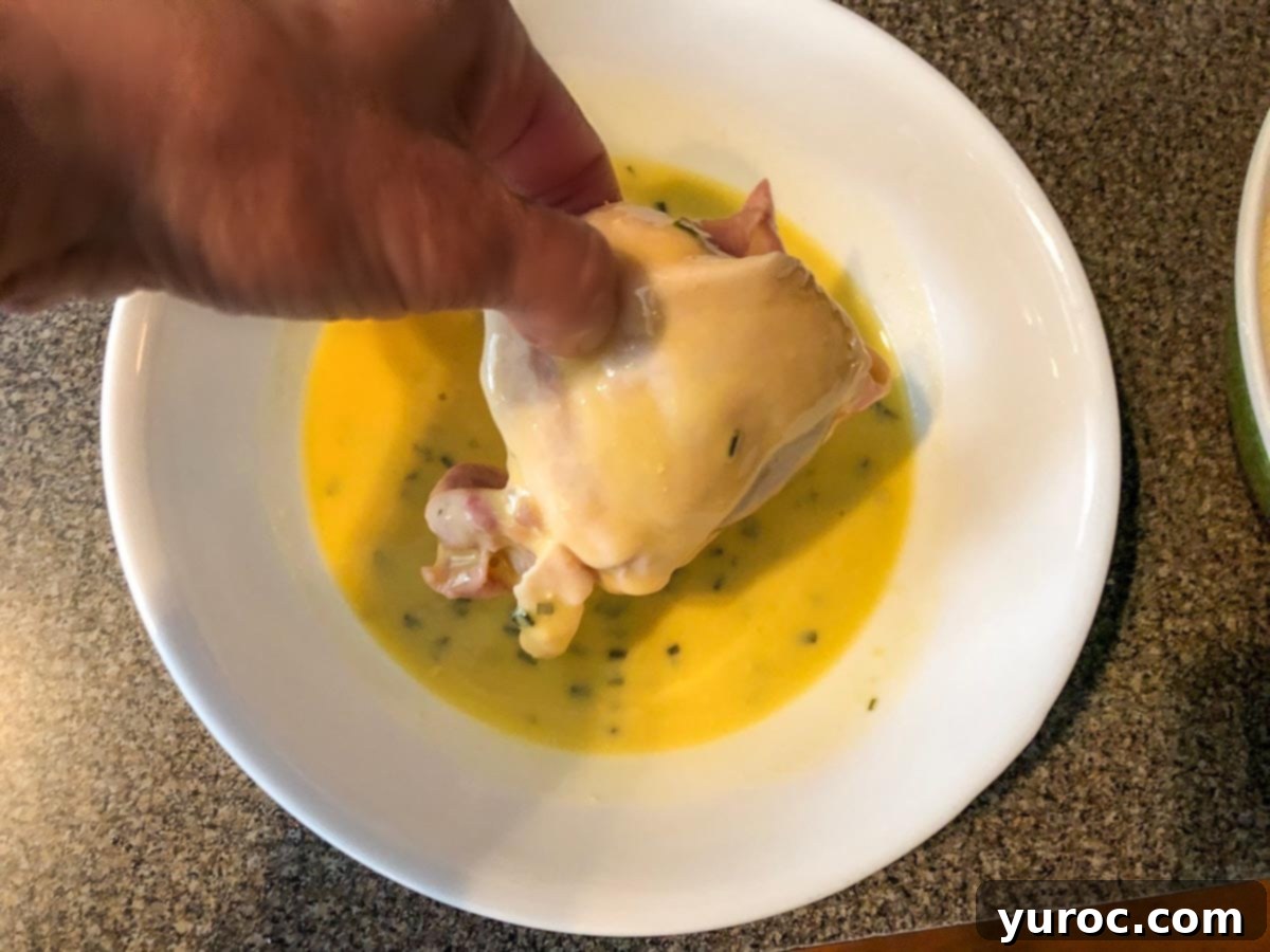 chicken being coated in egg mixture in white bowl