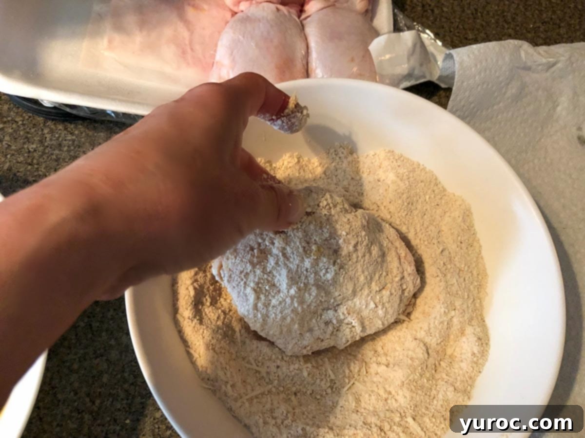 chicken being coated with breading mixture in white bowl
