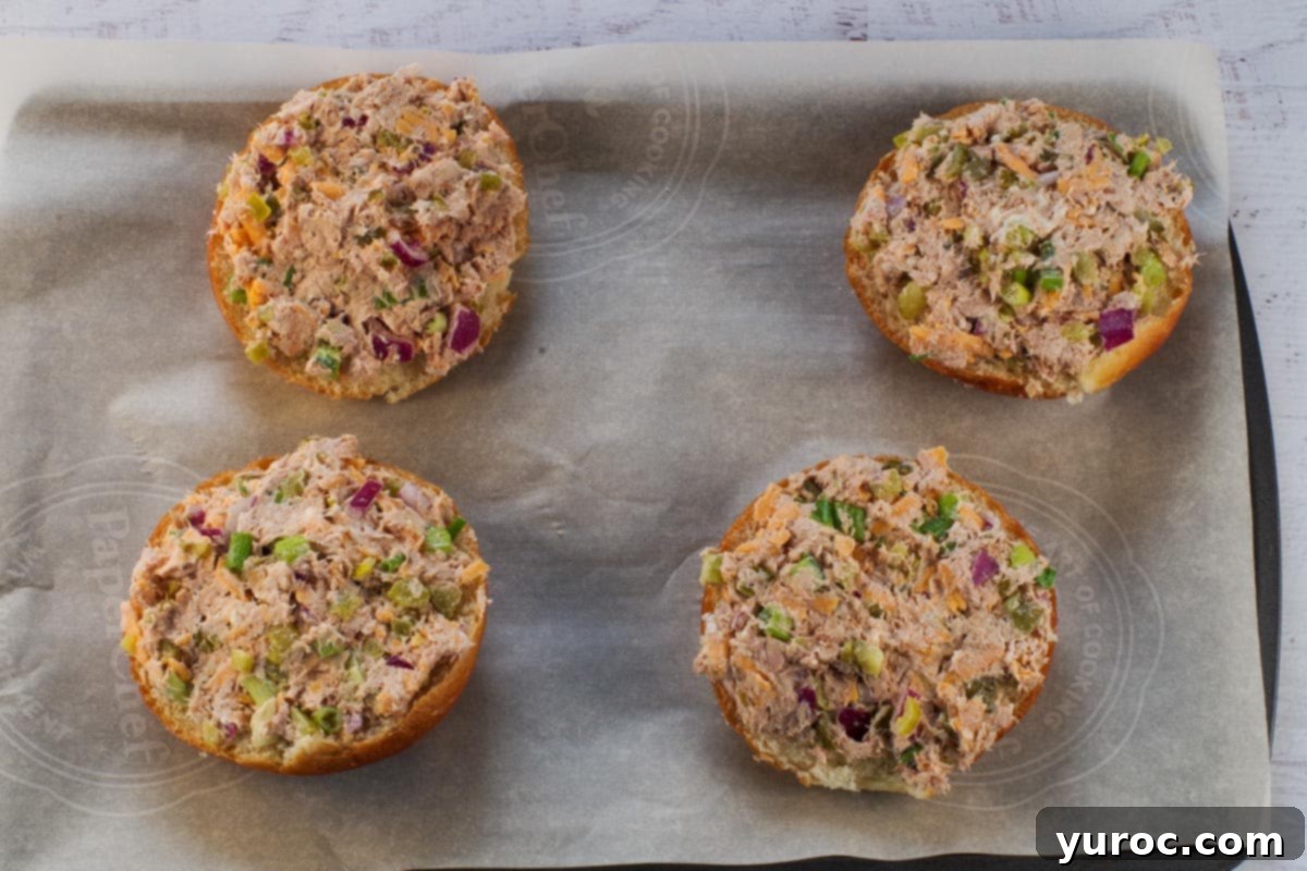 Buns topped with Tuna melt mixture on parchment lined baking sheet