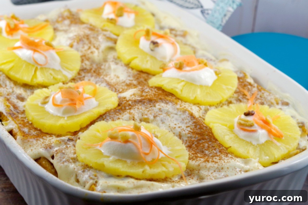 A beautiful, freshly baked Carrot Cake French Toast Casserole with a section removed. The casserole is adorned with cream cheese glaze, pineapple rings, generous dollops of whipped cream, and delicate carrot ribbons, showcasing a vibrant and appealing breakfast or brunch dish.