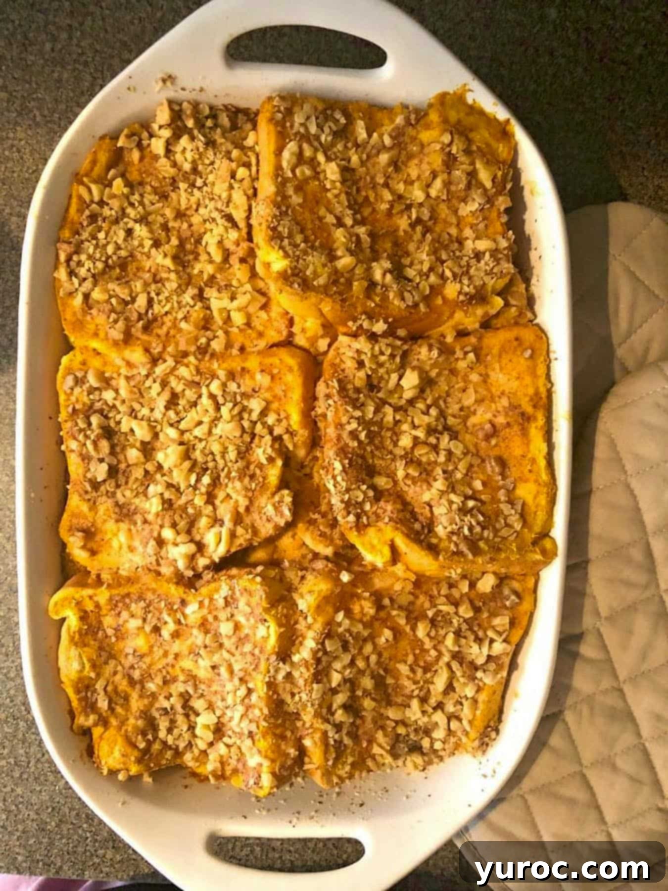 The final layer of bread in the casserole dish is now fully covered with the remaining French toast liquid mixture, and finely chopped walnuts are generously sprinkled over the top for added texture and flavor.