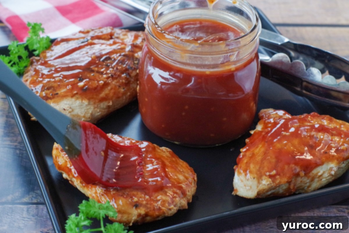 Quick and Easy Ketchup Brown Sugar BBQ Sauce 7 Perfectly grilled chicken breast pieces arranged around a bowl of homemade BBQ sauce, invitingly presented on a black platter.