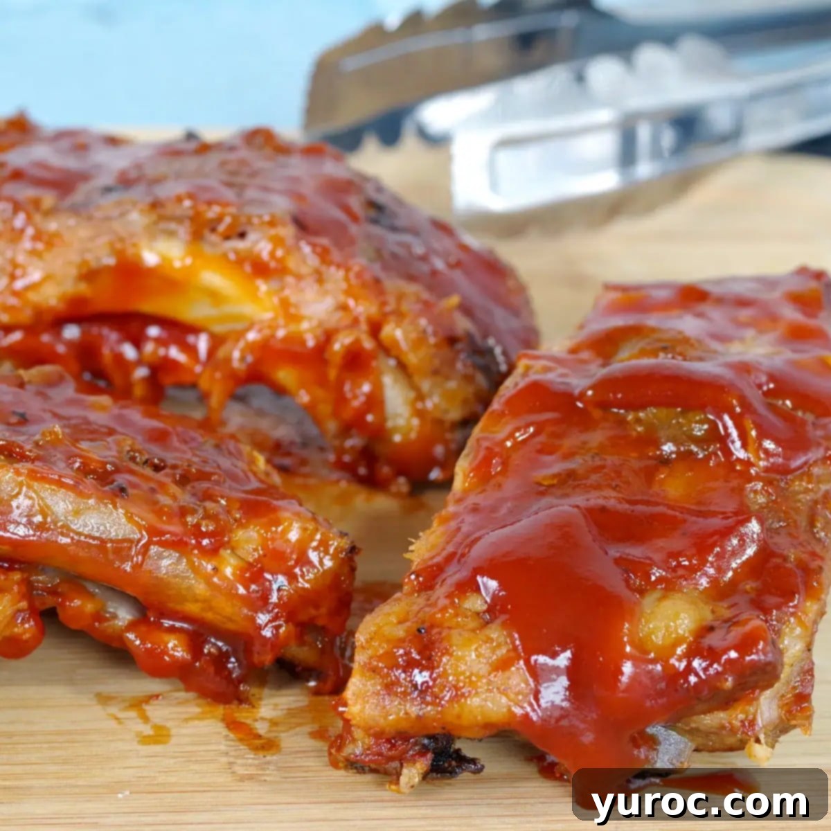 Quick and Easy Ketchup Brown Sugar BBQ Sauce 9 Tender slow cooker ribs with beer, beautifully arranged on a cutting board, with tongs resting in the background.