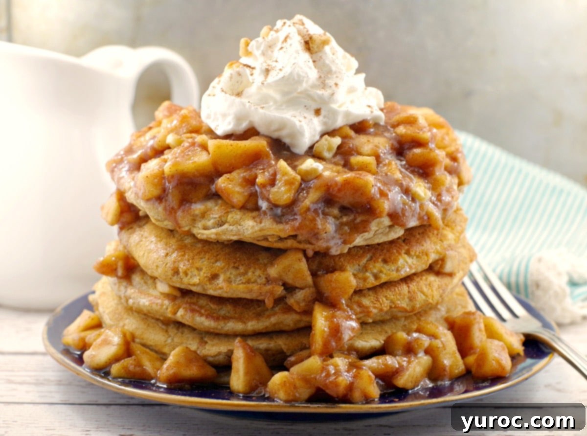 Stacked IHOP copycat harvest grain and nut pancakes with apple topping and whipped cream