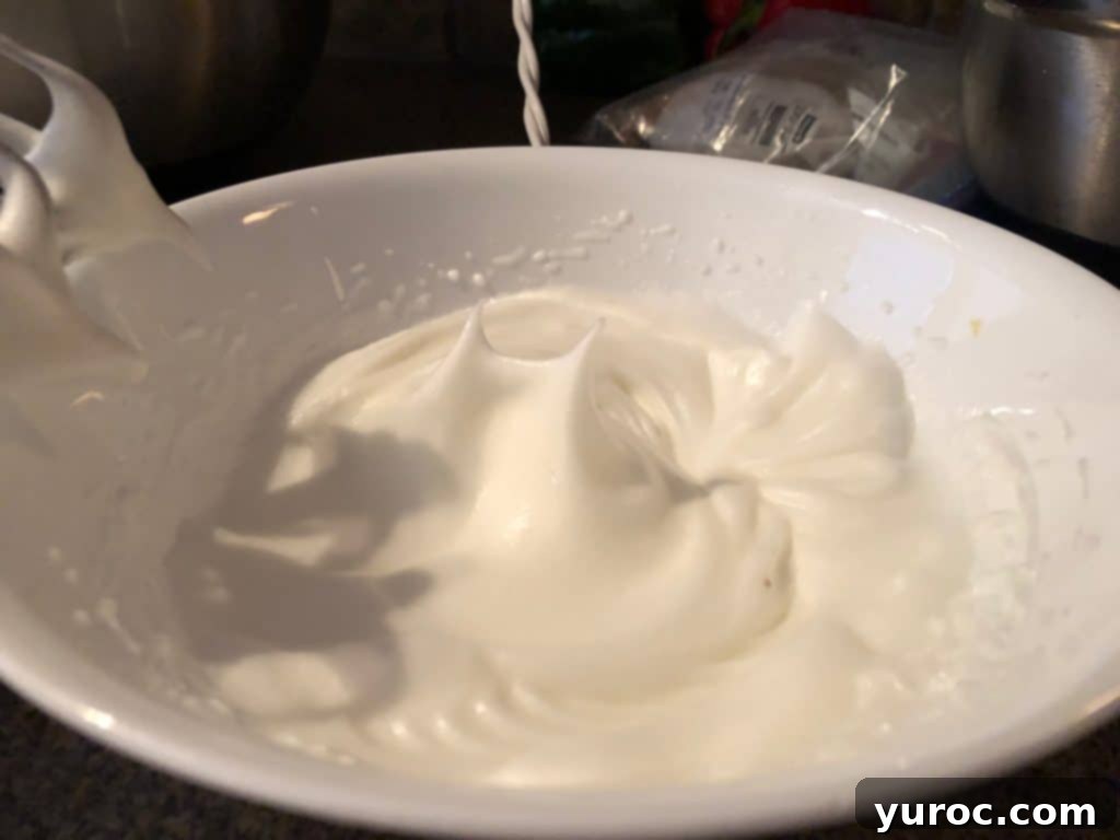 Egg whites beaten to stiff peaks in a white bowl