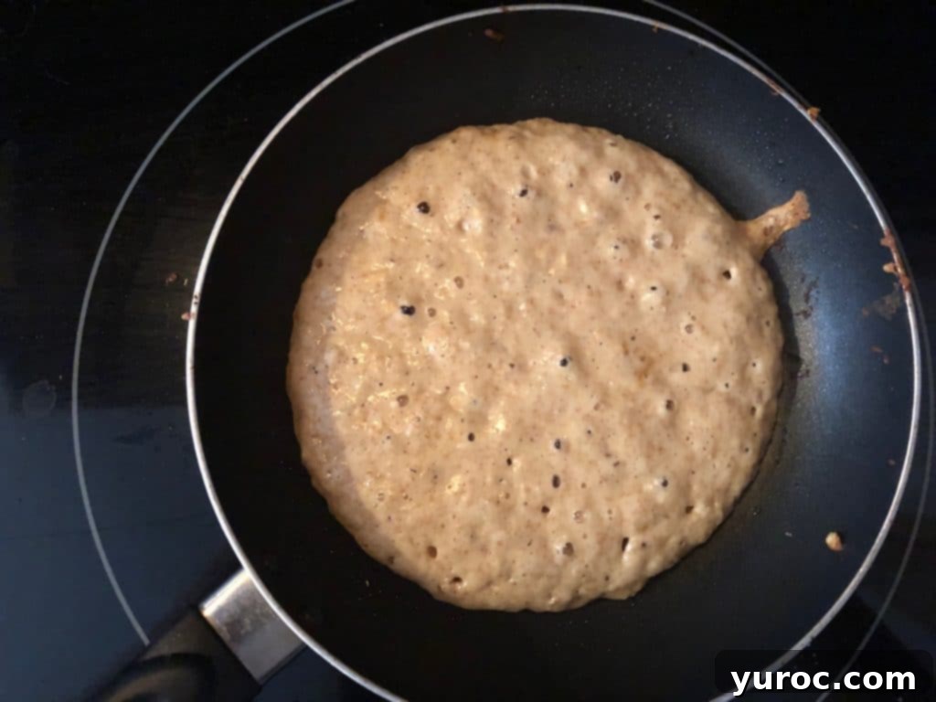 Pancake starting to bubble on the surface in a frying pan