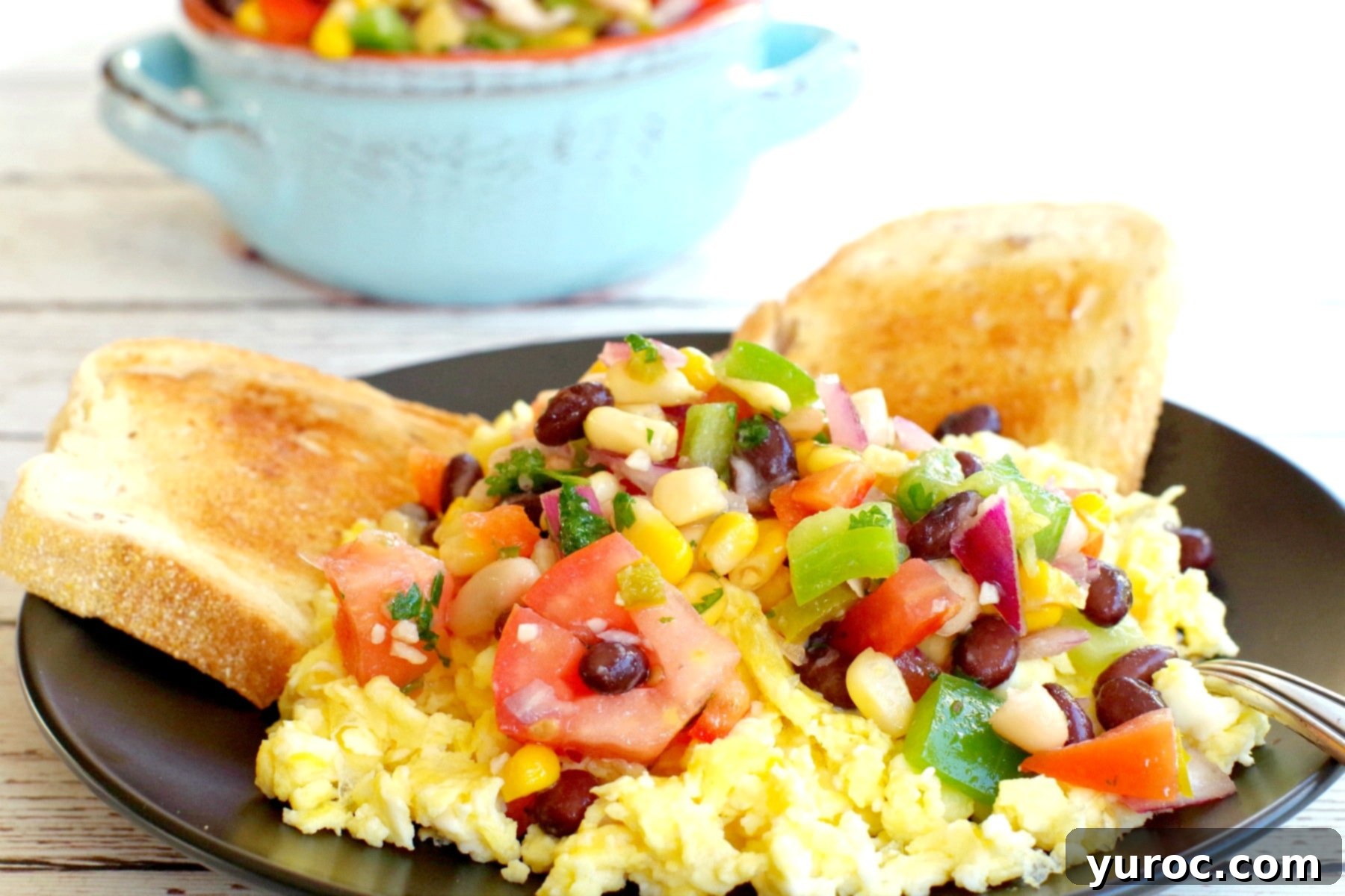 cowboy caviar dip on top of scrambled eggs with toast and dish of dip in the background