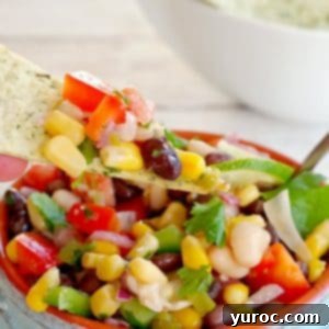 Cowboy Caviar Dip in a bowl with a chip being dipped in