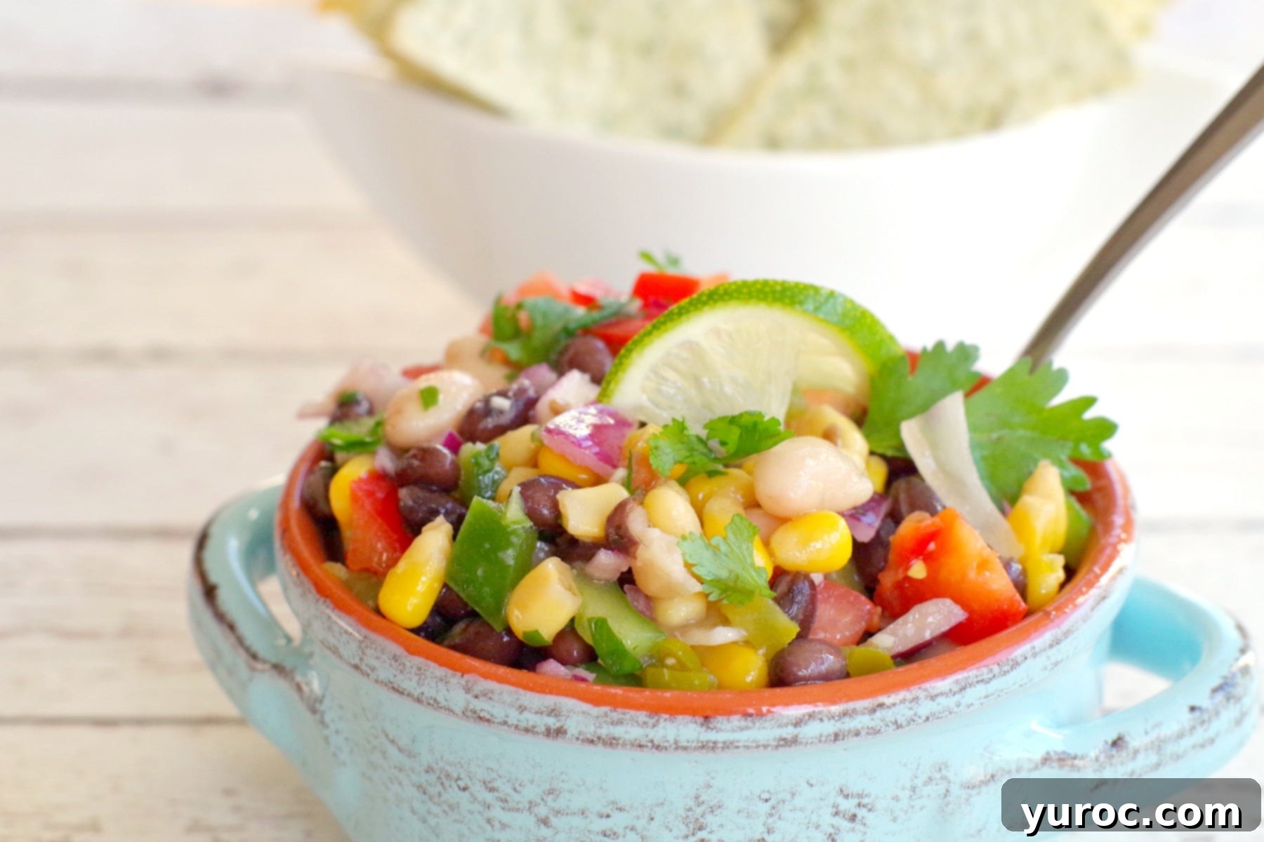 cowboy caviar in a blue bowl with tortilla chips in the background