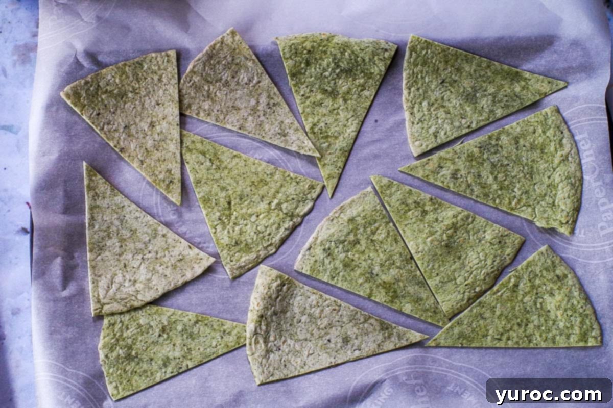 Tortilla triangles on a parchment covered baking sheet.