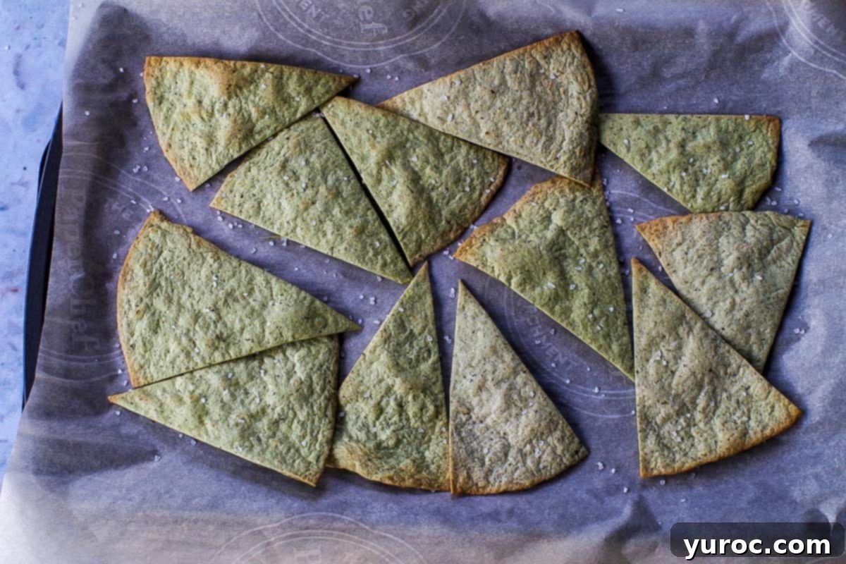 Baked tortilla triangles on a parchment covered baking sheet.