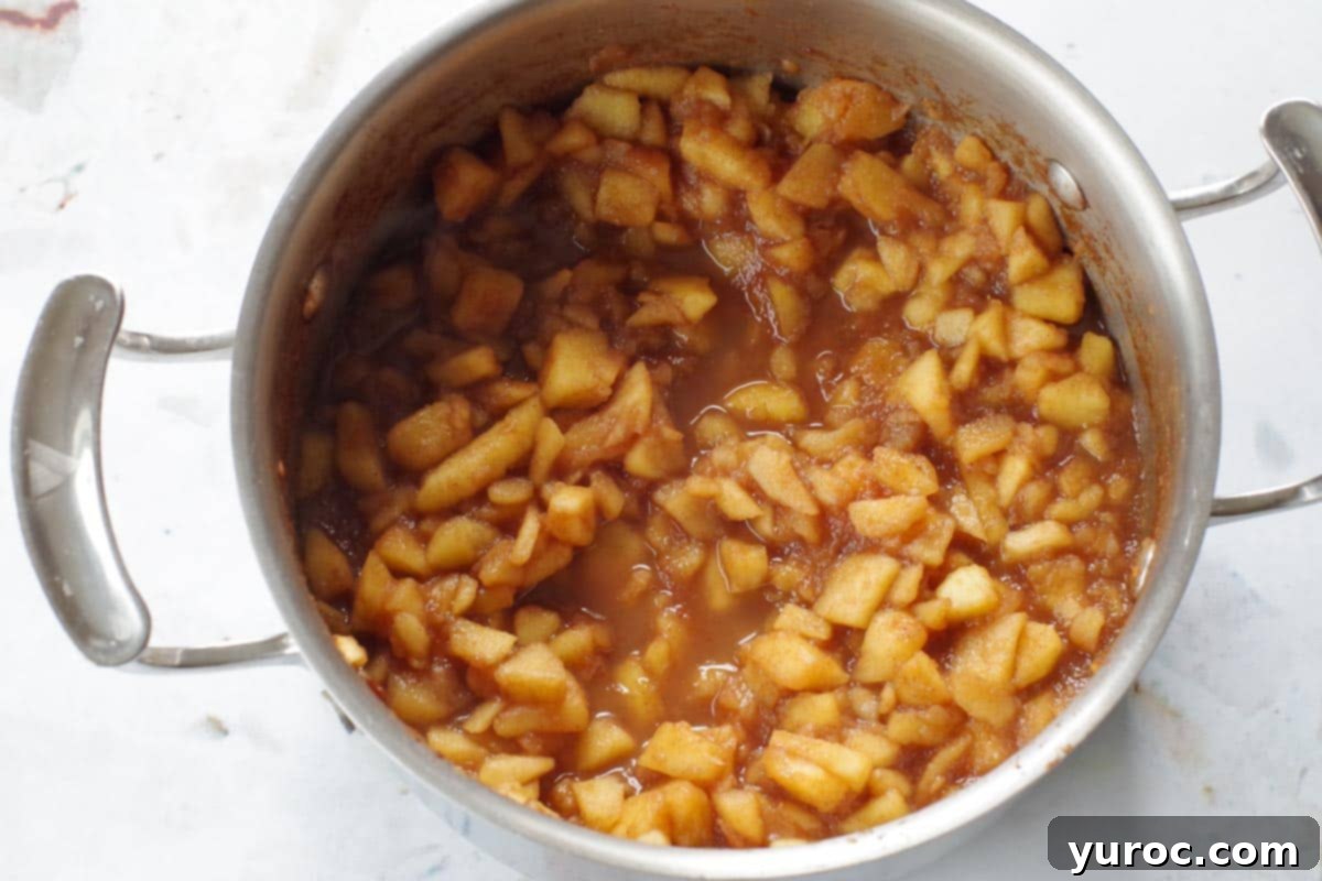 Warm Apple Cinnamon Topping 4 The apple cinnamon topping, cooked to perfection, simmering gently in a saucepan, showcasing its tender consistency.