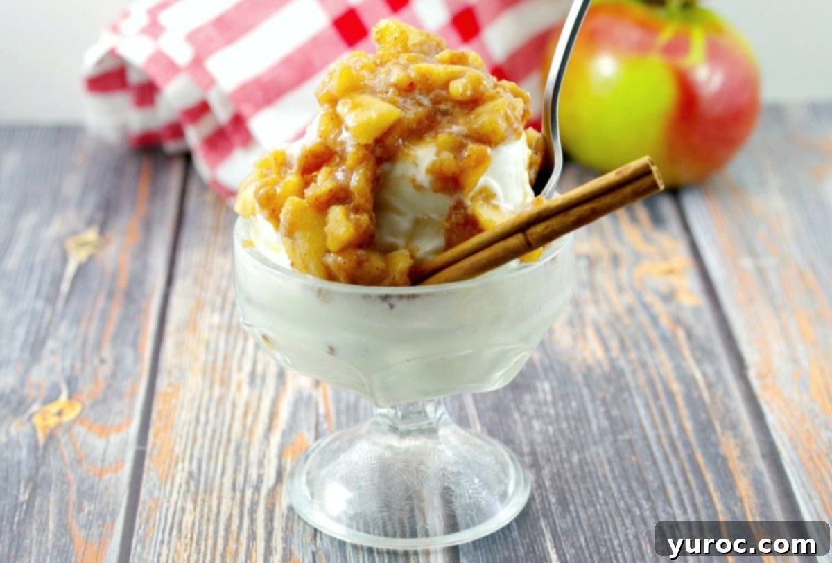 Warm Apple Cinnamon Topping 7 A close-up shot of apple cinnamon topping generously served on frozen yogurt in an ice cream dish, accompanied by a spoon, a cinnamon stick, a fresh apple, and a charming checkered cloth in the background, emphasizing its dessert appeal.