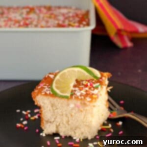 Tropical Lime Coconut Tres Leches 10 A slice of creamy coconut lime tres leches cake on a black plate with a fork, with the full cake in the background.