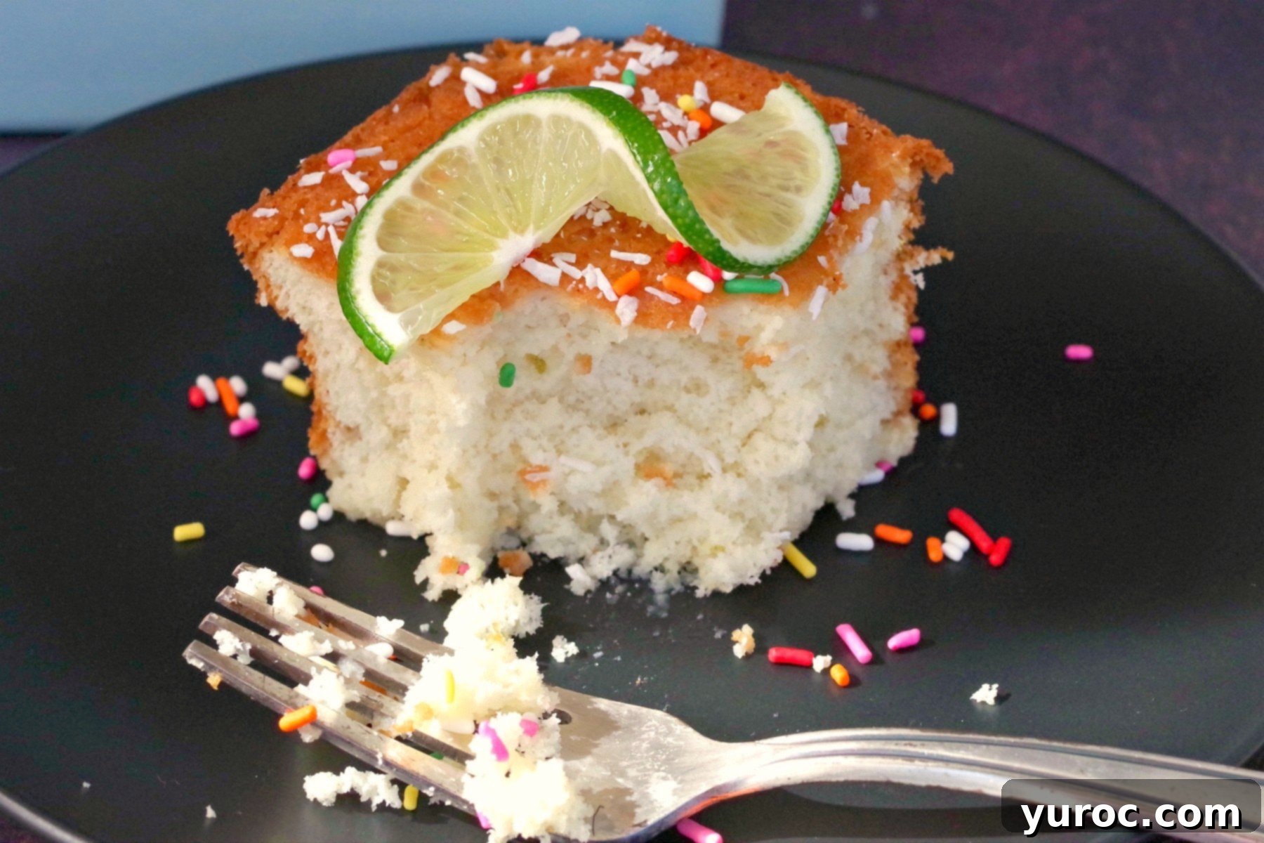 Tropical Lime Coconut Tres Leches 2 A partially eaten Tres Leches Cake with a fork, showing its moist texture and milky appearance.