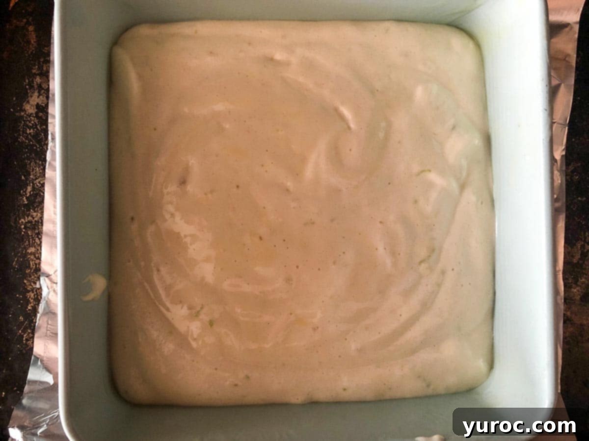 Tropical Lime Coconut Tres Leches 3 Coconut Tres Leche Cake batter evenly spread in a prepared 8x8 inch baking pan, ready for the oven.