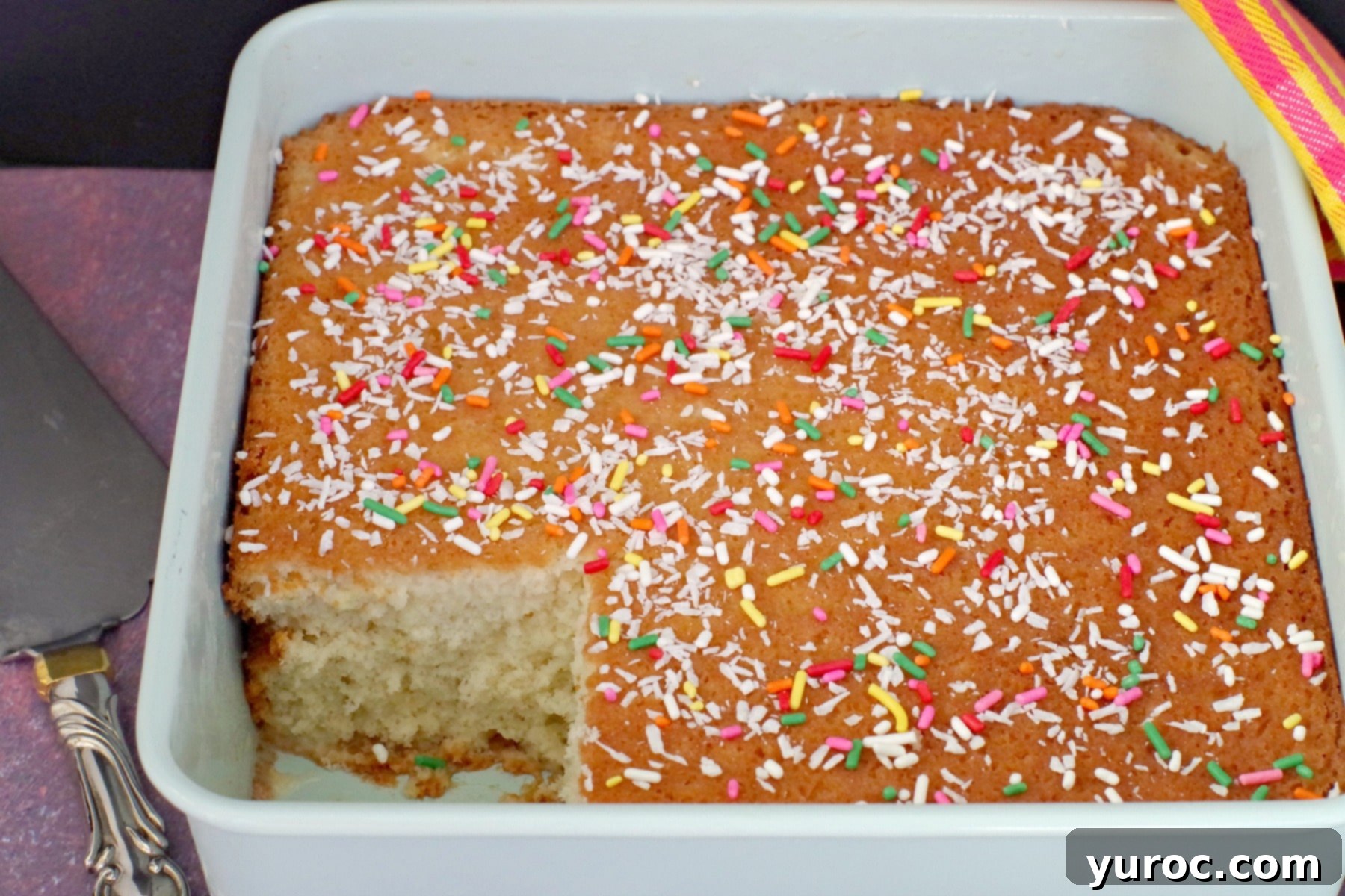 Tropical Lime Coconut Tres Leches 7 A Tres Leches Cake with a slice removed, revealing its moist interior and creamy texture.