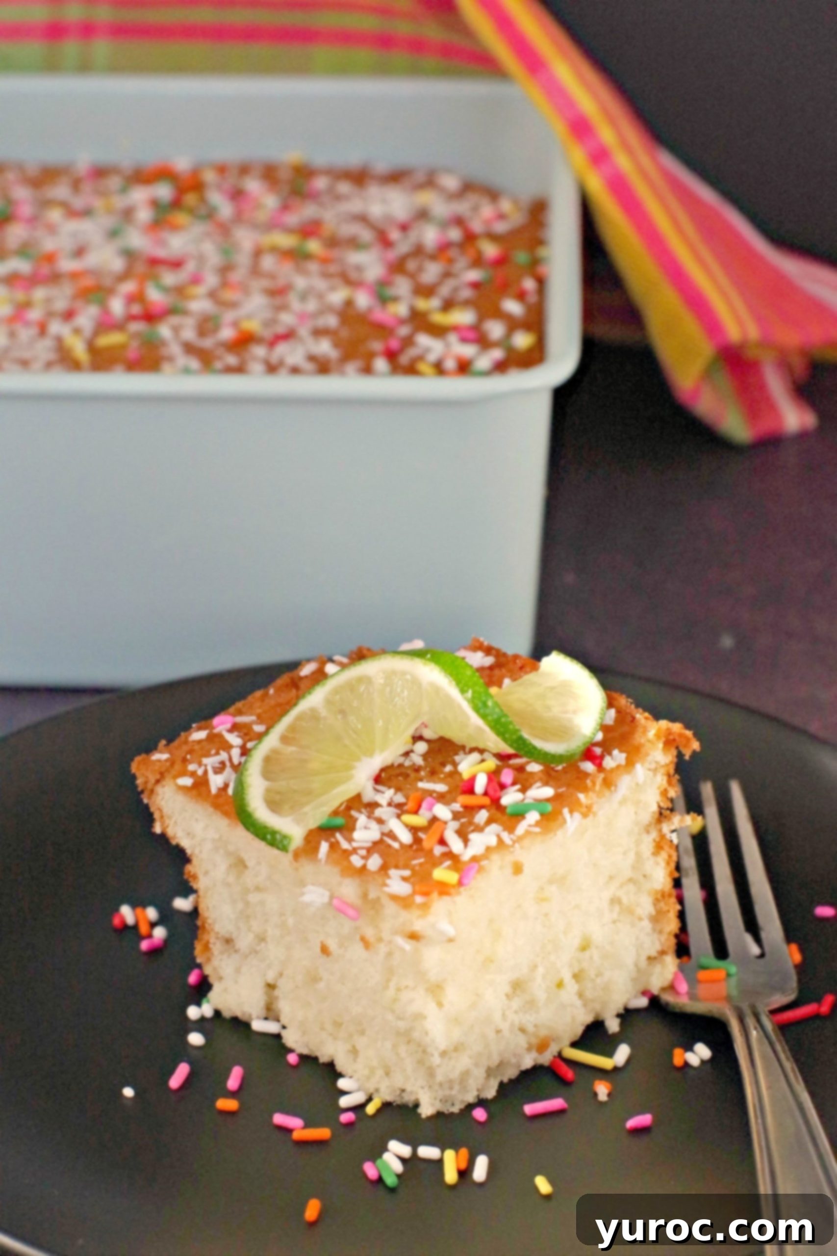 Tropical Lime Coconut Tres Leches 8 A whole Coconut Lime Tres Leches Cake in a baking pan, with a slice served on a plate in the foreground, ready to enjoy.