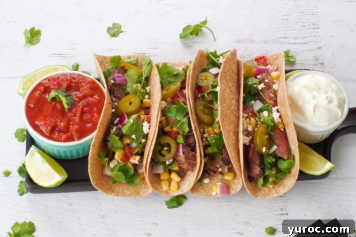 Tropical Lime Coconut Tres Leches 9 Close-up of delicious Air fryer steak tacos, garnished with salsa, sour cream, and lime wedges, presented on a sleek black serving tray.