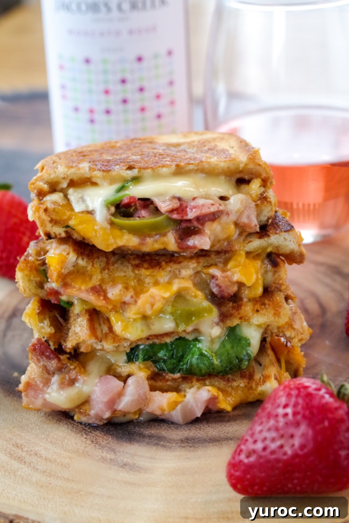 Strawberry Moscato grilled cheese on wooden tree platter with glass of moscato in background and strawberries