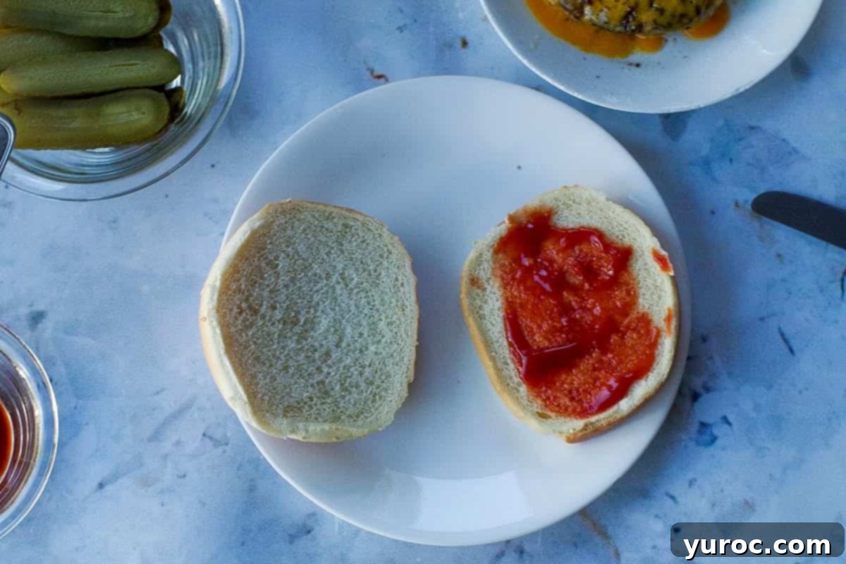Hamburger bun on a plate with ketchup on bottom side.