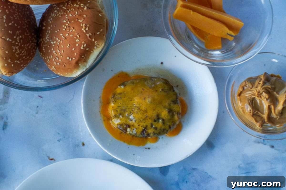 Cheese melted on cooked hamburger patty on a small white plate.