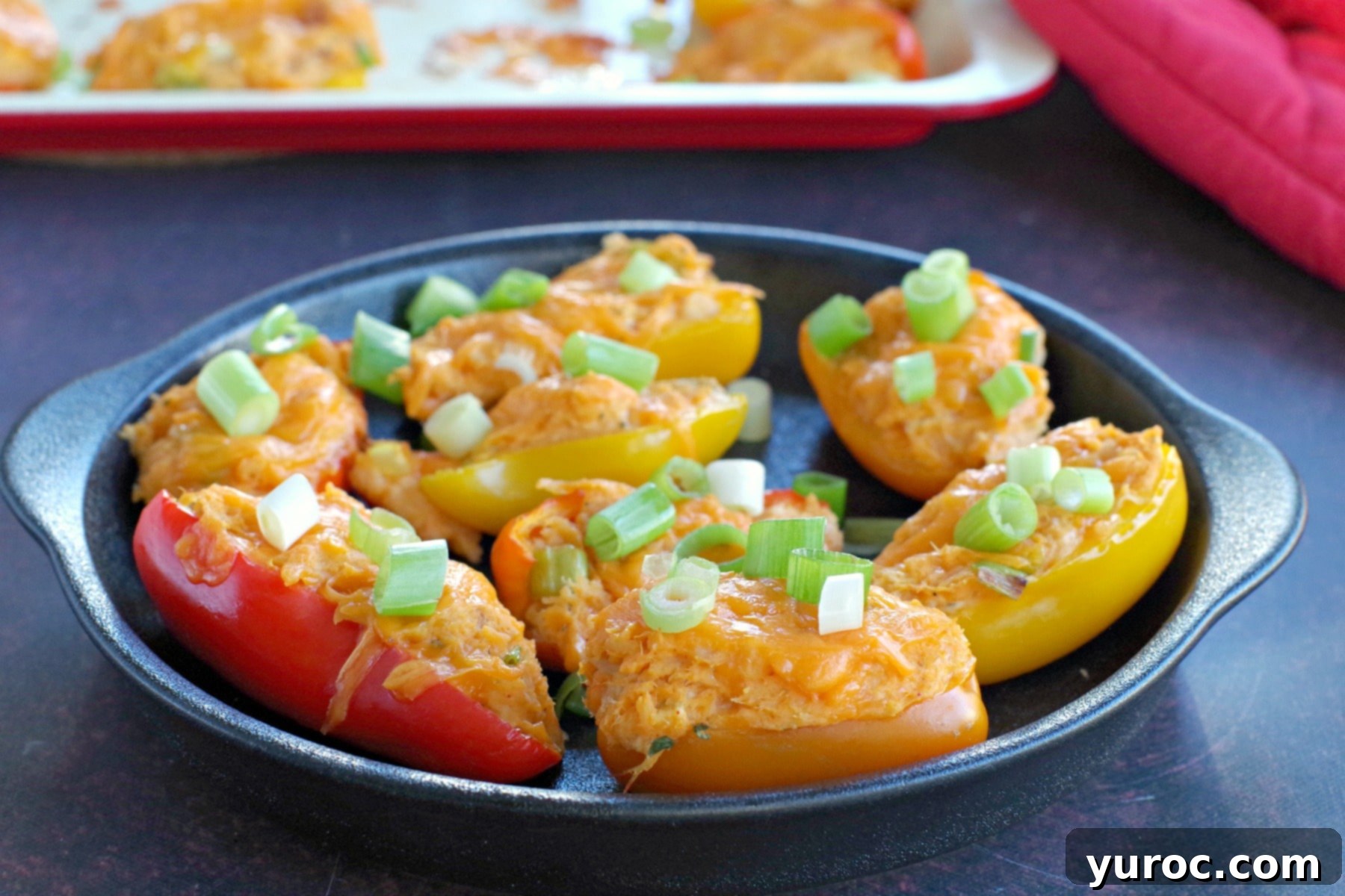 Zesty Buffalo Chicken Pepper Poppers 3 Healthy buffalo chicken stuffed mini peppers arranged artfully on a sleek black appetizer tray, with a baking sheet visible in the soft-focus background.