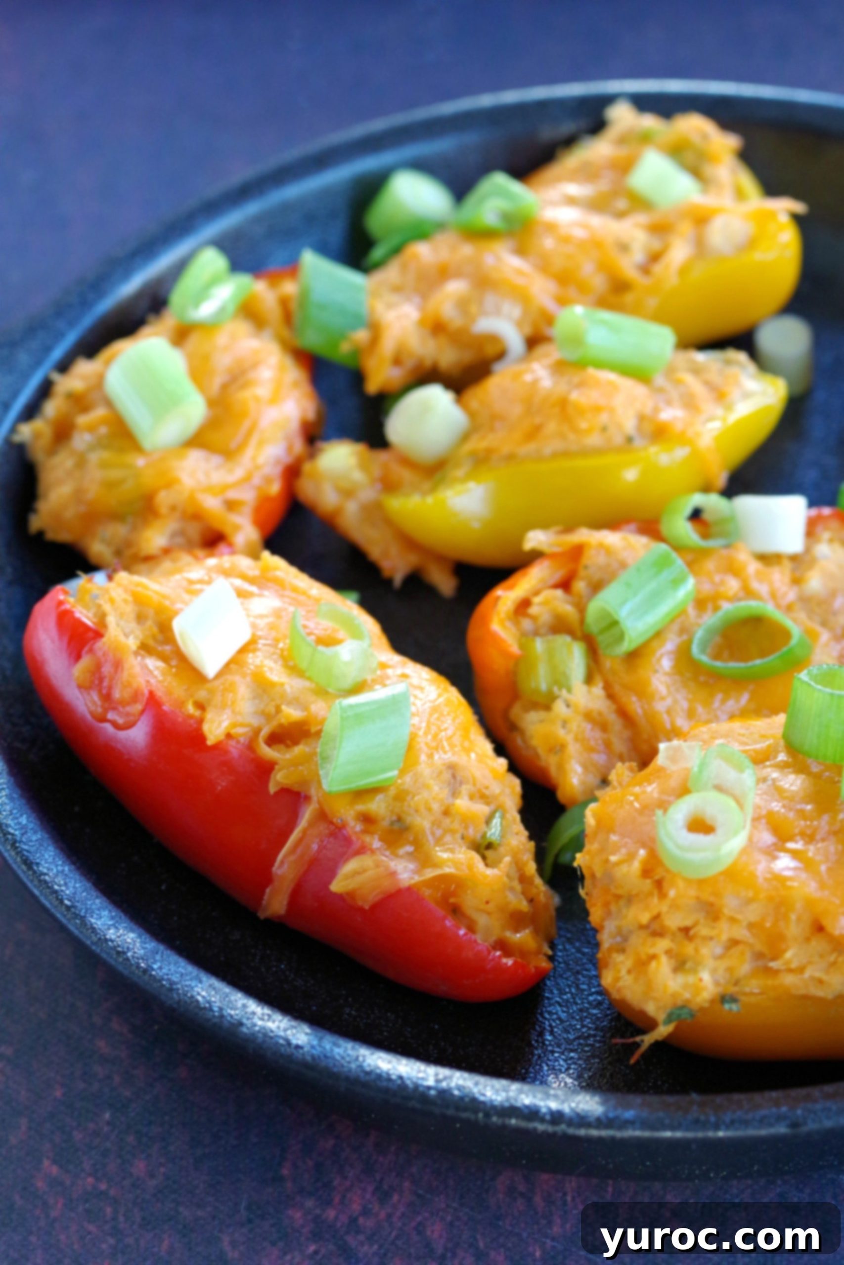 Zesty Buffalo Chicken Pepper Poppers 4 A close-up shot of half a dish filled with delicious chicken stuffed mini peppers, showcasing the vibrant colors and cheesy topping.