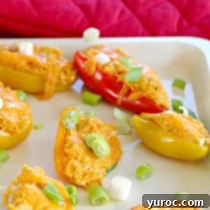 Zesty Buffalo Chicken Pepper Poppers 8 Stuffed mini peppers on an off-white baking sheet, showcasing the delicious appetizer ready for the oven.