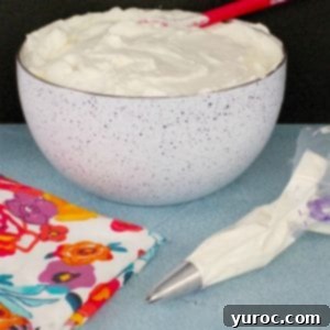 Pastry bag filled with stabilized whipped cream frosting and bowl of frosting in the background, ready for piping