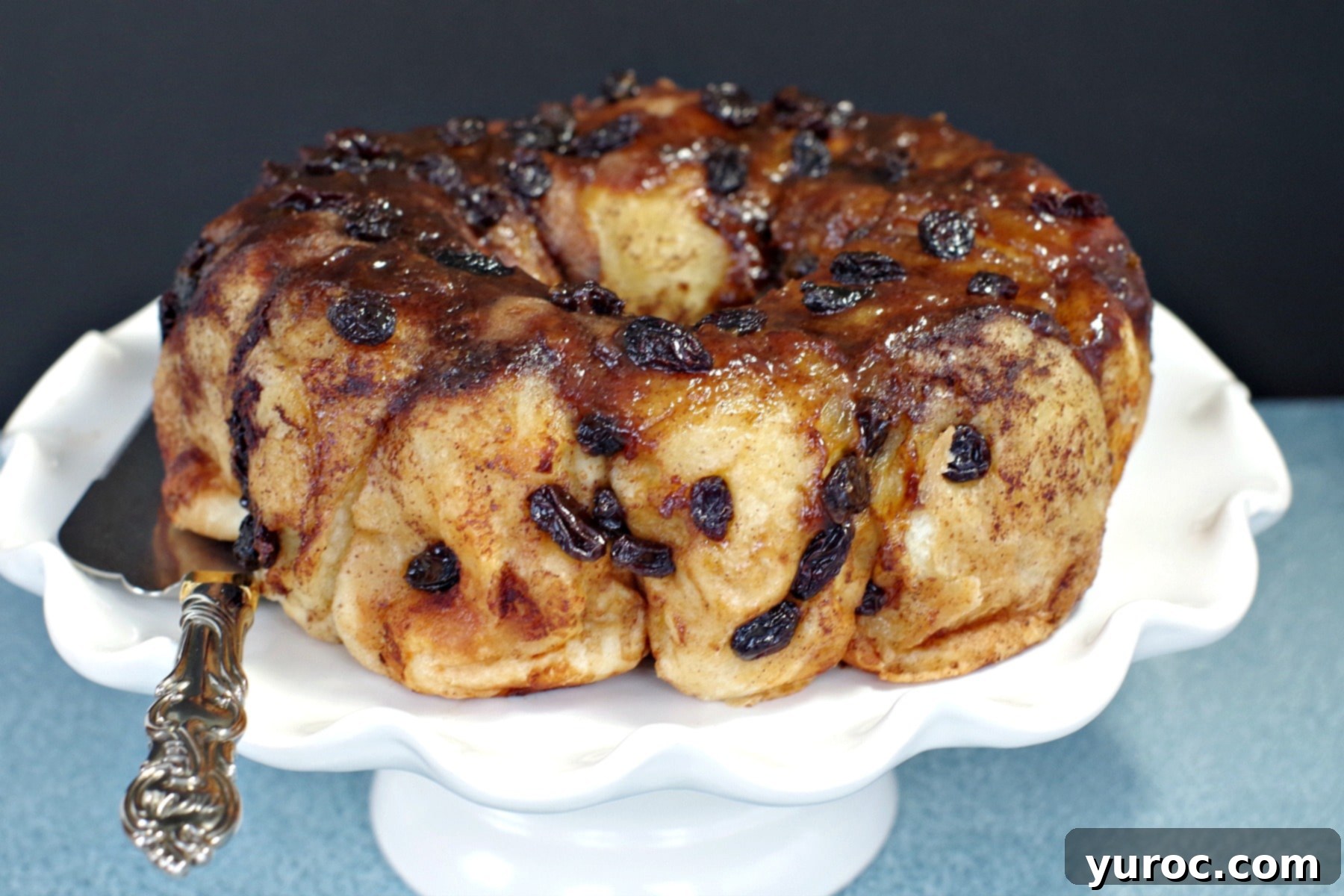 Overnight Caramel Cinnamon Buns 3 Overnight Cinnamon Sticky Buns on a white cake platter, showing the beautiful golden crust and glossy glaze.