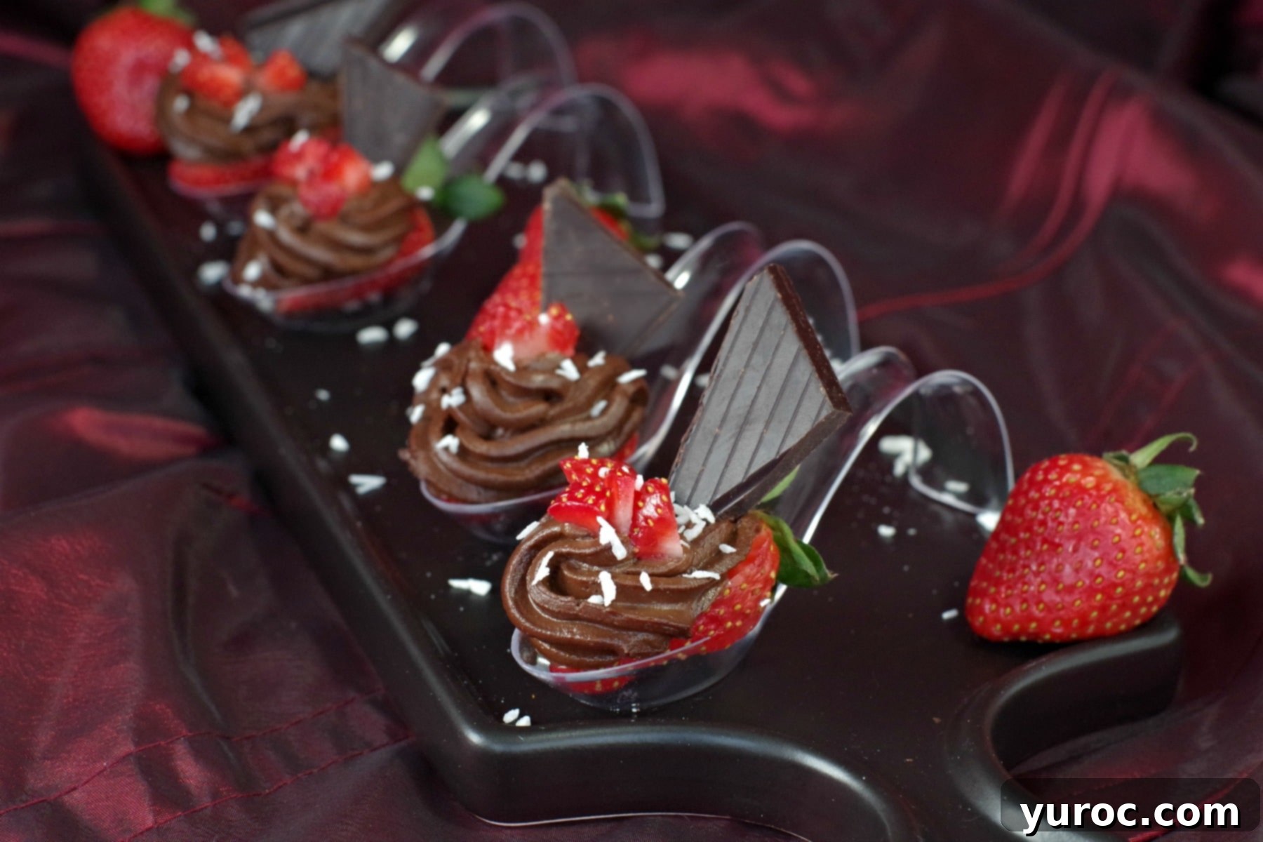 Four elegant chocolate avocado strawberry desserts on spoons, arranged beautifully on a black appetizer tray, ready to be served.