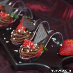 Four chocolate avocado strawberry desserts on spoons, elegantly displayed on a black appetizer tray, ready to be enjoyed.