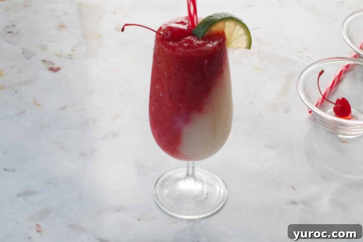 Miami vice garnished with lime wedge and maraschino cherry.